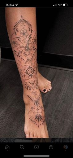 a woman's foot with flowers and leaves on the bottom part of her leg