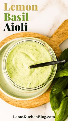 a glass jar filled with green liquid next to basil leaves