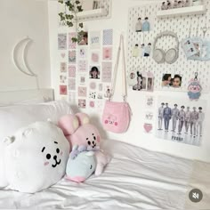 two stuffed animals sitting on top of a bed next to a wall with many pictures