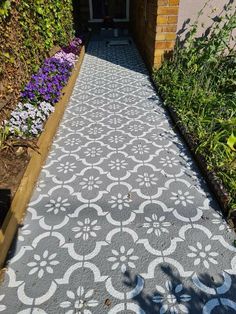 an outdoor walkway made out of cement with flowers growing on the side and in front