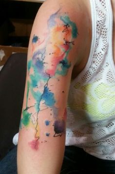 a woman's arm with colorful ink on it and a white shirt behind her