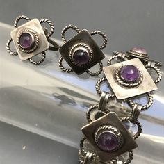 "Vintage ~ Pre eagle mark ~ sterling silver linked panel bracelet and matching screw-back earrings ~ Each panel has a bezel set amethyst cab in center with applied wire work around it ~ Bracelet ends with a simple \"J\" hook clasp ~ Very well made piece with beautiful details . Marked Silver Mexico on the backside . Measurements : Bracelet is 7 3/4 inches x 7/8 inches max width . Earrings are 7/8 inches x 7/8 inches Weighs 47 grams on my weighing scale . Condition : Overall Good vintage conditio Bracelet Ends, Weighing Scale, Amethyst Bracelet, Vintage Mexican, Hook Clasp, Wire Work, Screw Back Earrings, Bezel Setting, Amethyst