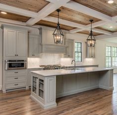 a large kitchen with an island and wooden floors in front of two windows on the wall