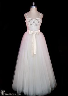 a white dress with a bow on the waist and neckline, sitting on a mannequin