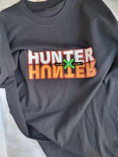 a black shirt with the word hunter spelled in orange and green on it's chest