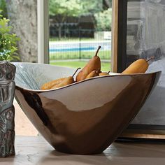 a bowl filled with pears sitting on top of a table next to a vase