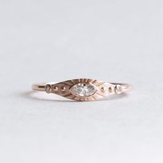 a gold ring with an evil eye and two diamonds on the side, sitting on a white surface