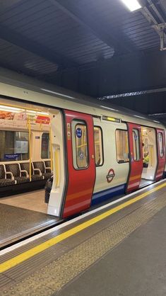 a red, white and blue train pulling into the station