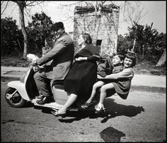 three people riding on the back of a scooter