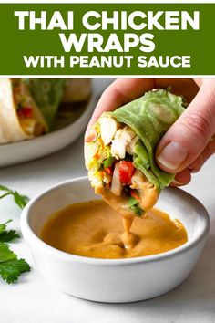 a hand holding a tortilla wrap over a bowl of peanut sauce and garnished with cilantro