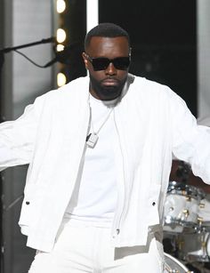 a man in white clothes and sunglasses on stage