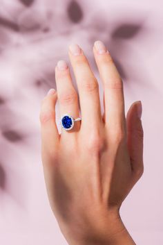 a woman's hand with a ring on her finger and a blue stone in the middle