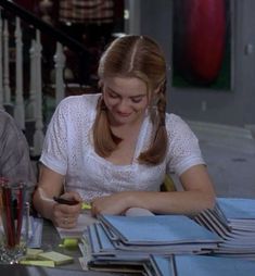 two people sitting at a table with papers and pens