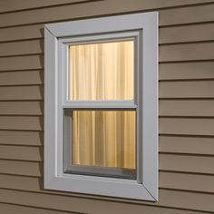 an open window on the side of a house that is painted beige and has vertical blinds