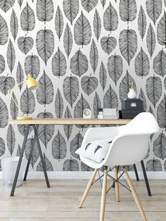 a desk with a chair, lamp and wallpaper in black and white leaves on it