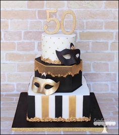 a 50th birthday cake decorated with masquerades and gold foil on a table