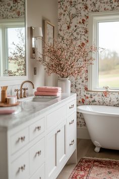 a white bath tub sitting next to a bathroom sink under a window with flowers on it