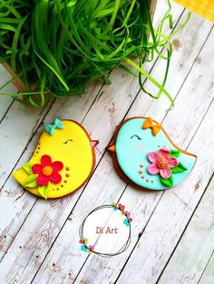 two decorated cookies sitting on top of a wooden table next to a potted plant