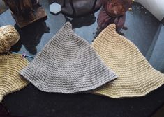 three crocheted hats sitting on top of a table next to yarn and other items