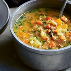 a bowl of soup with carrots, potatoes and meat in it on a table