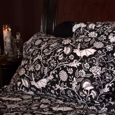 a bed with black and white comforter next to a night stand filled with candles