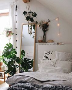 a bedroom with white walls and plants in the corner, along with a large mirror on the wall