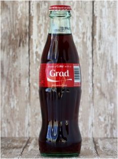 a close up of a bottle of soda on a wooden table with planks in the background