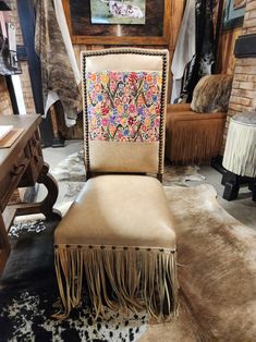 a tan chair with fringes on it in a room filled with furniture and rugs