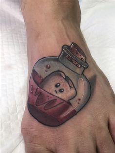 a person's foot with a tattoo on it and a bottle in the shape of a heart