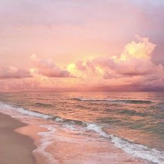 an ocean beach with waves coming in to shore and the sun going down over the clouds