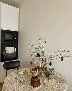 the table is set with food and flowers in front of an oven on the wall