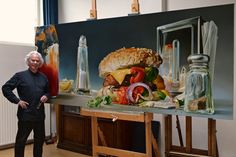 a man standing next to a painting of a hamburger and ketchup on a table