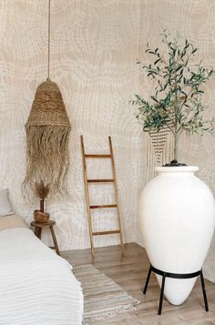 a white vase sitting on top of a hard wood floor next to a bed and ladder