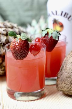 two glasses filled with watermelon and strawberries on top of a table next to a pineapple