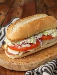 a sub sandwich sitting on top of a wooden cutting board