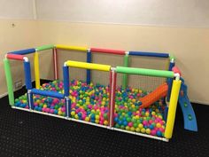 an indoor play area with colorful balls in the net and slides on the wall behind it