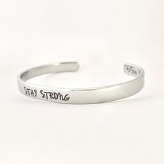 STAY STRONGThis inspirational hand stamped cuff bracelet makes the perfect gift to give or treat for yourself. The cuff is 1/4 inch by 6 inches and is bent to fit most wrists. My items are hand stamped by me, making them a unique gift. Each letter is stamped individually and may not line up exactly adding to the charm and uniqueness of the gift. Visit my shop to view all of my other items by clicking here: https://www.etsy.com/shop/GemsbyJohnnaPlease see my shop header for current production tim Adjustable Stamped Minimalist Cuff Bracelet, Minimalist Stamped Adjustable Cuff Bracelet, Everyday Hand Stamped Bangle Cuff Bracelet, Adjustable Personalized Bangle For Everyday, Adjustable Hand Stamped Bracelets As Personalized Gift, Adjustable Hand Stamped Bracelets For Personalized Gift, Adjustable Stamped Cuff Bracelet For Everyday, Meaningful Adjustable Stamped Bracelets, Adjustable Engraved Cuff Bracelet