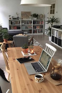 an open laptop computer sitting on top of a wooden table in front of a window