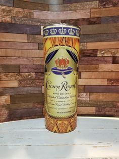 a can of beer sitting on top of a table next to a wooden wall behind it