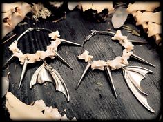 Uniquely crafted bone creoles with bat wings & spikes. The earrings are clearly noticeable on the ear due to their size! The bones and spikes make a slight rattling noise on the ear! This is handmade jewelry made from real animal bones that I turn into individual jewelry! Each bone is an absolute one-of-a-kind piece, so slight deviations are possible! The creoles can also vary slightly in thickness I'll be happy to package your order as a gift! Please select gift packaging during the ordering process ;)) Width approx. 6 cm Length approx. 11 cm Creoles diameter 5 cm Colour: Silver / Natural white Material: Metal / Real animal bones Native American Bone Jewelry, Handmade Bone Jewelry For Halloween, Handmade Gothic Horned Jewelry, Real Bone Jewelry, Animal Bone Jewelry, Real Bones, Witch Earrings, Bone Earrings, Bone Crafts