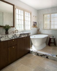 a large bathroom with marble counter tops and wooden cabinets, along with an oval bathtub