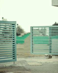 two metal gates open on the side of a road with grass and trees in the background