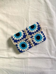 a blue and white crocheted case sitting on top of a white bed sheet