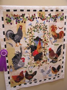 a quilted wall hanging with chickens and roosters on it's sides, along with a purple ribbon