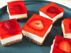 four pieces of dessert on a plate with strawberries and cheesecake toppings in the middle