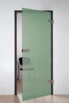 an open glass door in the corner of a room with a chair and table behind it