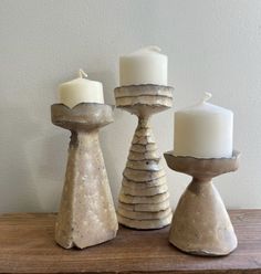 three candles sitting on top of a wooden table next to each other and one candle in the middle