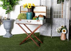 an old suitcase is sitting on a stand with flowers and vases in the background