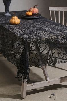 the table is covered with black lace and pumpkins