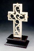 a white cross with an intricate design on it's side sitting on a black stand